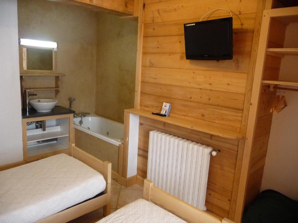une petite salle de bains avec un lit et une baignoire, ainsi qu'une télévision. dans l'établissement Apart'hotel & Spa "La Destière", à La Giettaz