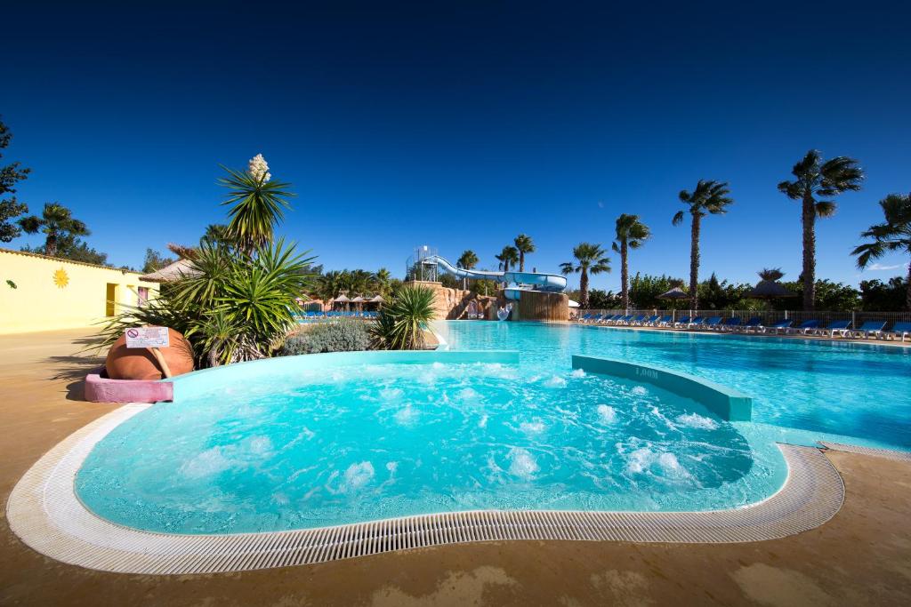 une piscine dans un complexe hôtelier avec des palmiers dans l'établissement Camping Club l'Air Marin, à Vias