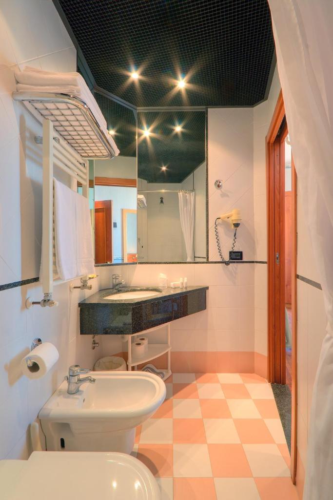 une salle de bain avec toilettes, lavabo et miroir dans l'établissement Hotel Palace, à Senigallia