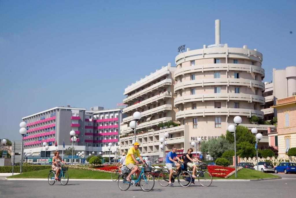 un groupe de personnes faisant du vélo dans une ville dans l'établissement Hotel Palace, à Senigallia