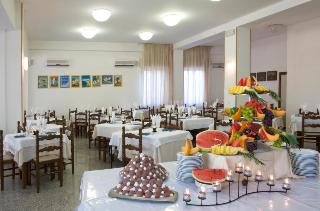 une salle à manger avec des tables et des chaises blanches dans l'établissement Hotel Confort, à Cattolica