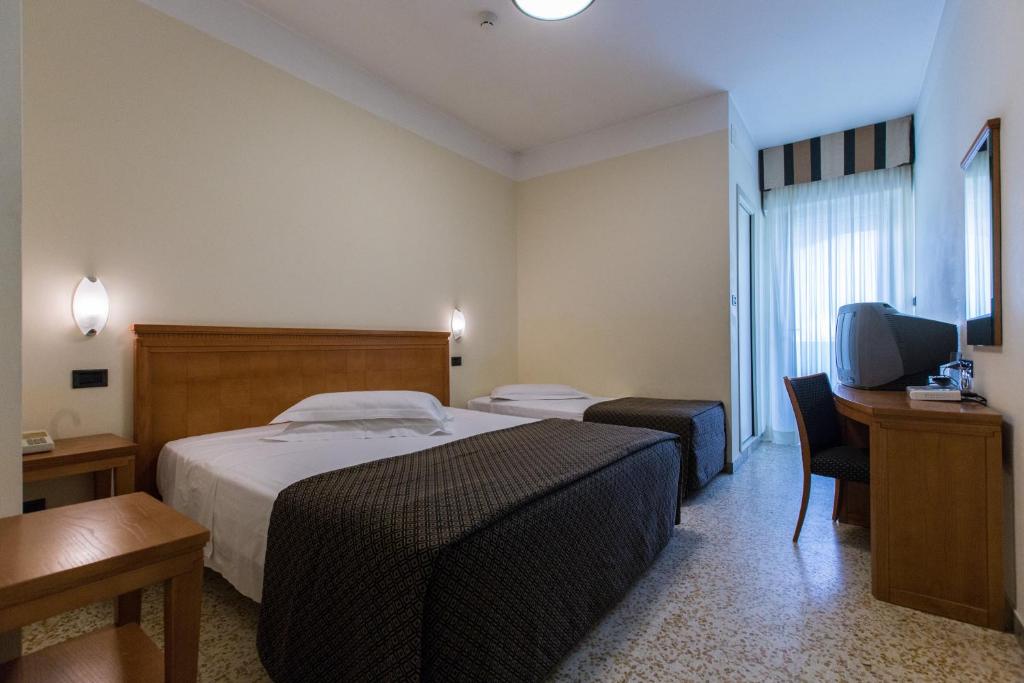 une chambre d'hôtel avec un lit, un bureau et une télévision dans l'établissement Nautilus, à Riccione
