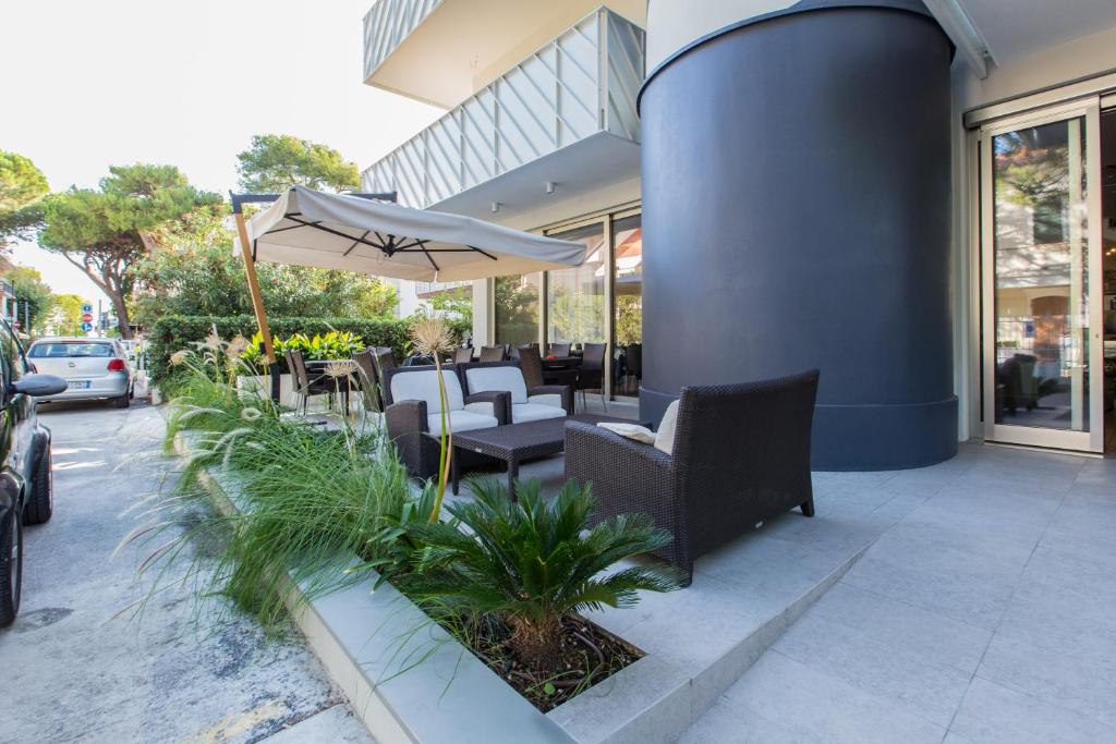 une terrasse avec des chaises et un parasol en face d'un bâtiment dans l'établissement Nautilus, à Riccione