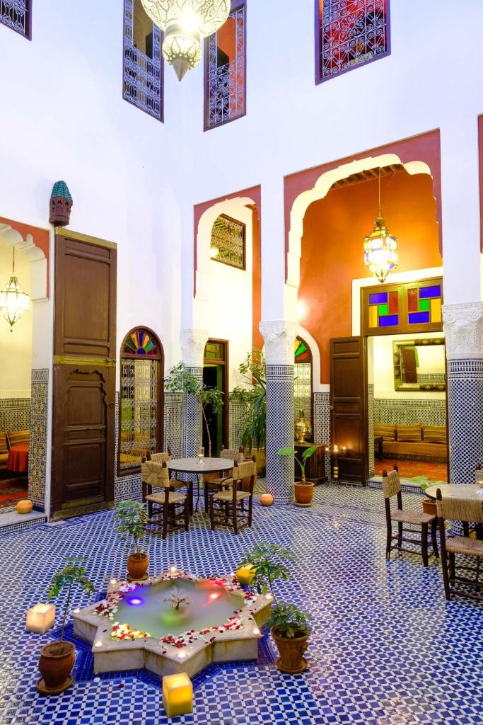 - une cour avec des tables, des chaises et une table fleurie dans l'établissement Riad Tafilalet, à Fès