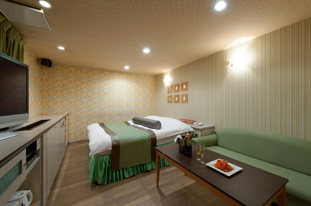 une chambre d'hôtel avec un lit et un canapé dans l'établissement ホテル ブランチャペルクリスマス 四日市, à Yokkaichi