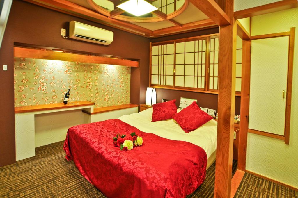 - une chambre avec un lit doté de draps rouges et d'oreillers rouges dans l'établissement Hotel Omochabako (Love Hotel), à Kurume