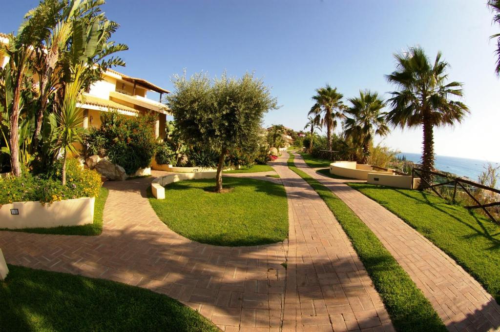 une passerelle devant une maison plantée de palmiers dans l'établissement Hotel Villaggio Cala Di Volpe, à Capo Vaticano