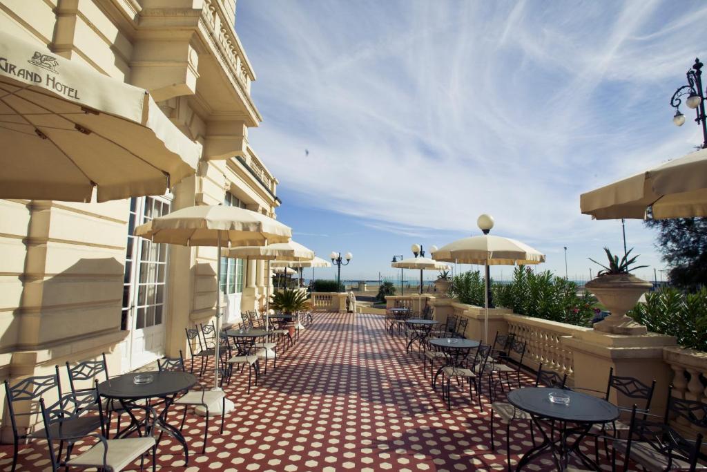 un patio extérieur avec tables, chaises et parasols dans l'établissement Grand Hotel Cesenatico, à Cesenatico