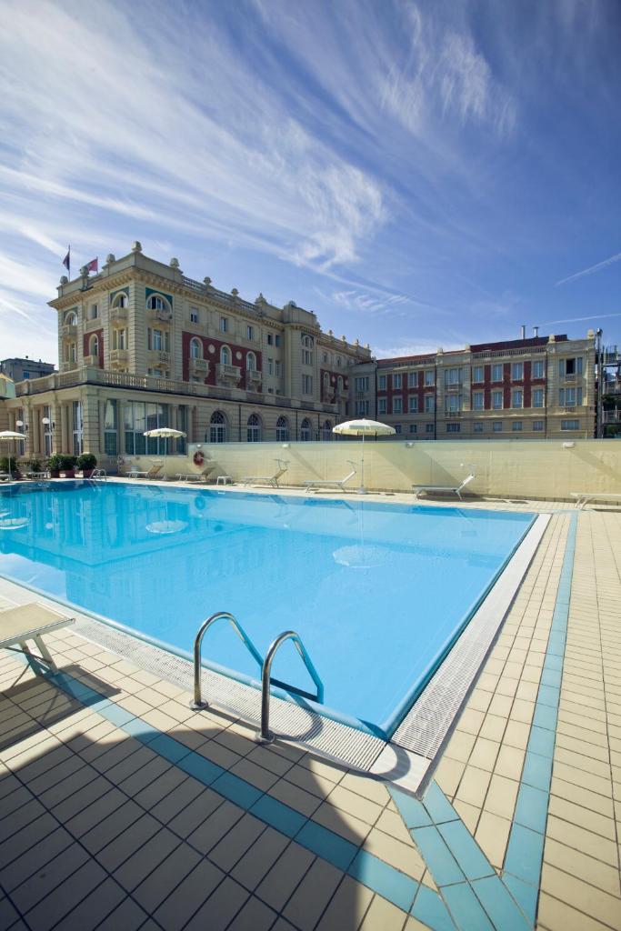 une grande piscine devant un immeuble dans l'établissement Grand Hotel Cesenatico, à Cesenatico