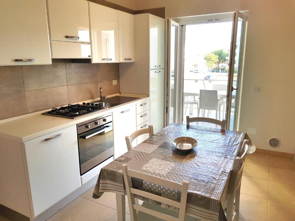 une cuisine avec une table et une cuisinière et une table et des chaises dans l'établissement La Rotonda Sul Mare, à Vieste