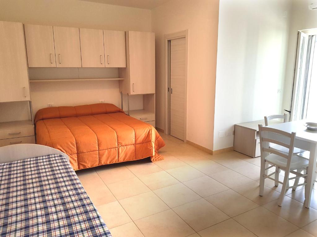 - une chambre avec un lit orange, une table et des chaises dans l'établissement La Rotonda Sul Mare, à Vieste