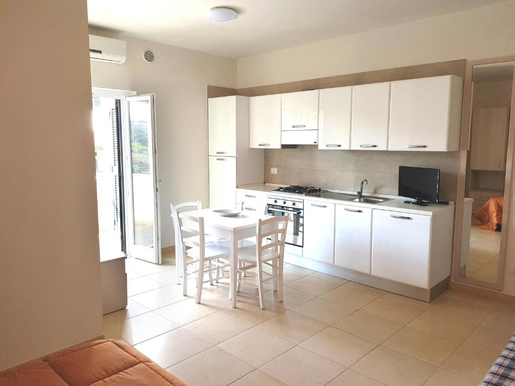 une cuisine avec des armoires blanches et une table et des chaises dans l'établissement La Rotonda Sul Mare, à Vieste 18 autres photos