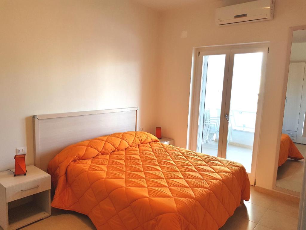 - une chambre avec un lit et une couette en orange dans l'établissement La Rotonda Sul Mare, à Vieste