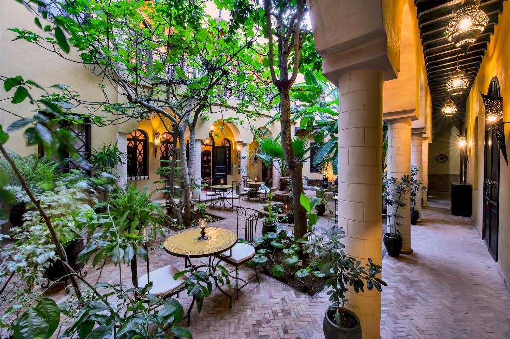 une cour avec une table, des chaises et des arbres dans l'établissement Riad Soleil D'orient, à El Jadida