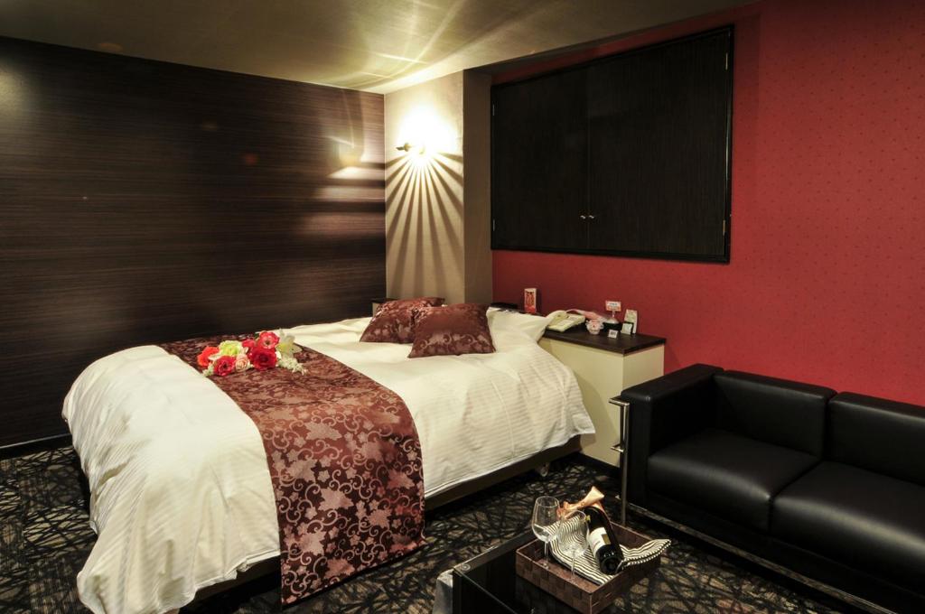 une chambre d'hôtel avec un lit et un canapé dans l'établissement Hotel Cube (Love Hotel), à Kitakyūshū