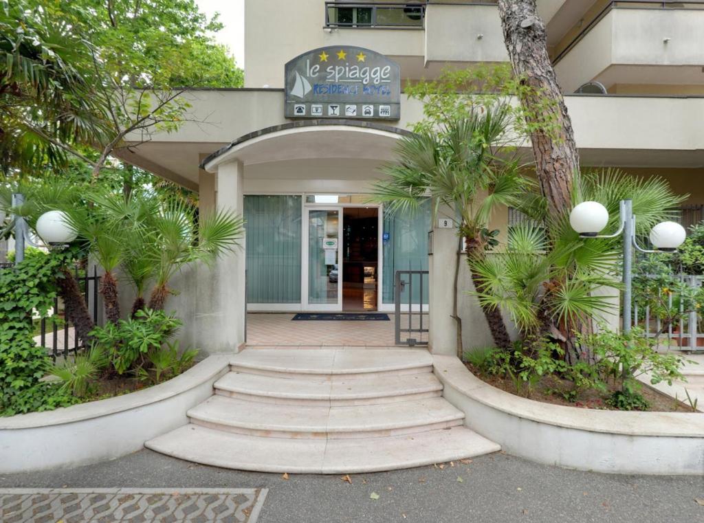 un accès à un bâtiment avec des palmiers devant lui dans l'établissement Residence le Spiagge, à Rimini