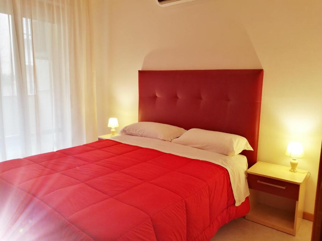 un lit rouge dans une chambre avec deux lampes dans l'établissement Aparthotel Costa Paradiso, à Lido Adriano