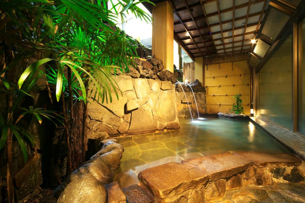 une piscine au milieu d'une maison avec un mur de roche dans l'établissement Kasuitei Ooya, à Fujikawaguchiko