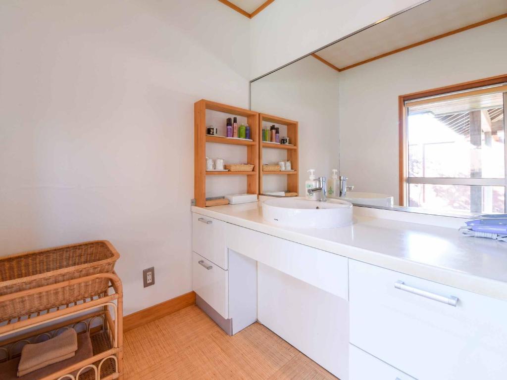 une salle de bain blanche avec un lavabo et une fenêtre dans l'établissement Spa&Resort Kujukuri Taiyou-no-sato, à Chosei