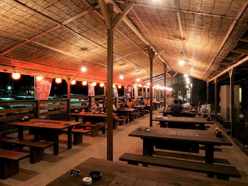 un restaurant avec des tables en bois et des gens assis à des tables dans l'établissement Spa&Resort Kujukuri Taiyou-no-sato, à Chosei