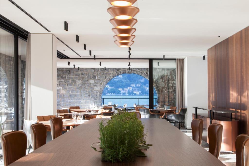 une salle à manger avec tables et chaises et une grande fenêtre dans l'établissement Il Sereno Lago di Como, à Torno