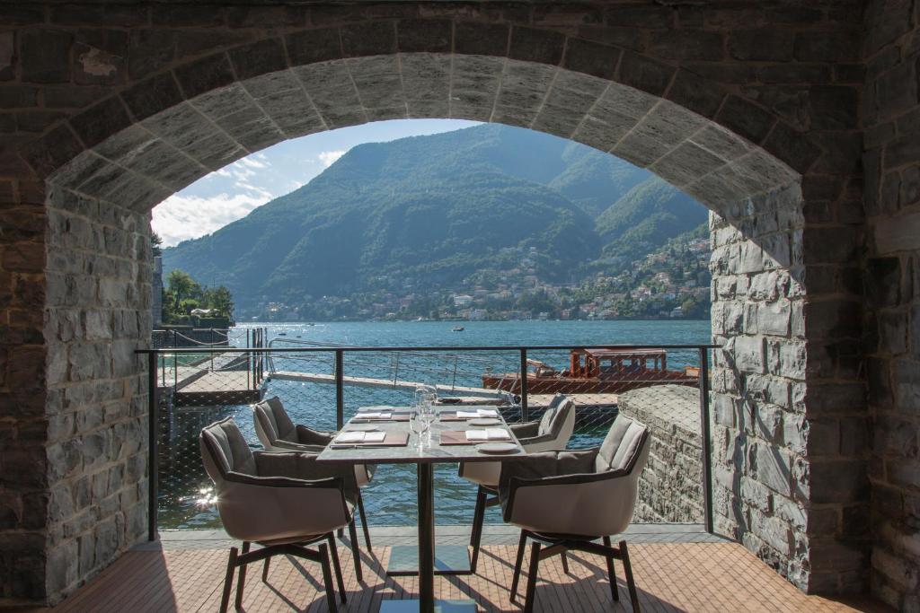 une table et des chaises sur un balcon avec vue sur l'eau dans l'établissement Il Sereno Lago di Como, à Torno