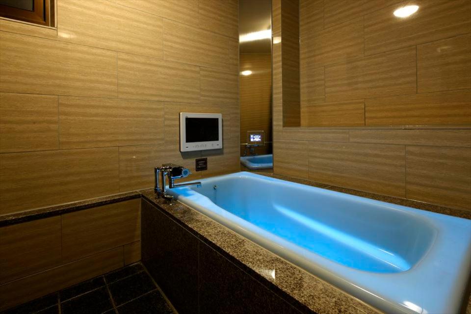 La salle de bains est pourvue d'une grande baignoire bleue et d'une télévision. dans l'établissement Hotel Waltz Okazaki (Adult Only), à Okazaki