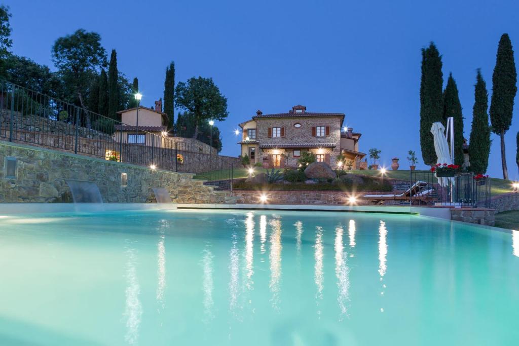 une grande piscine d'eau en face d'une maison dans l'établissement Poggio Pellicciaia, à Arezzo