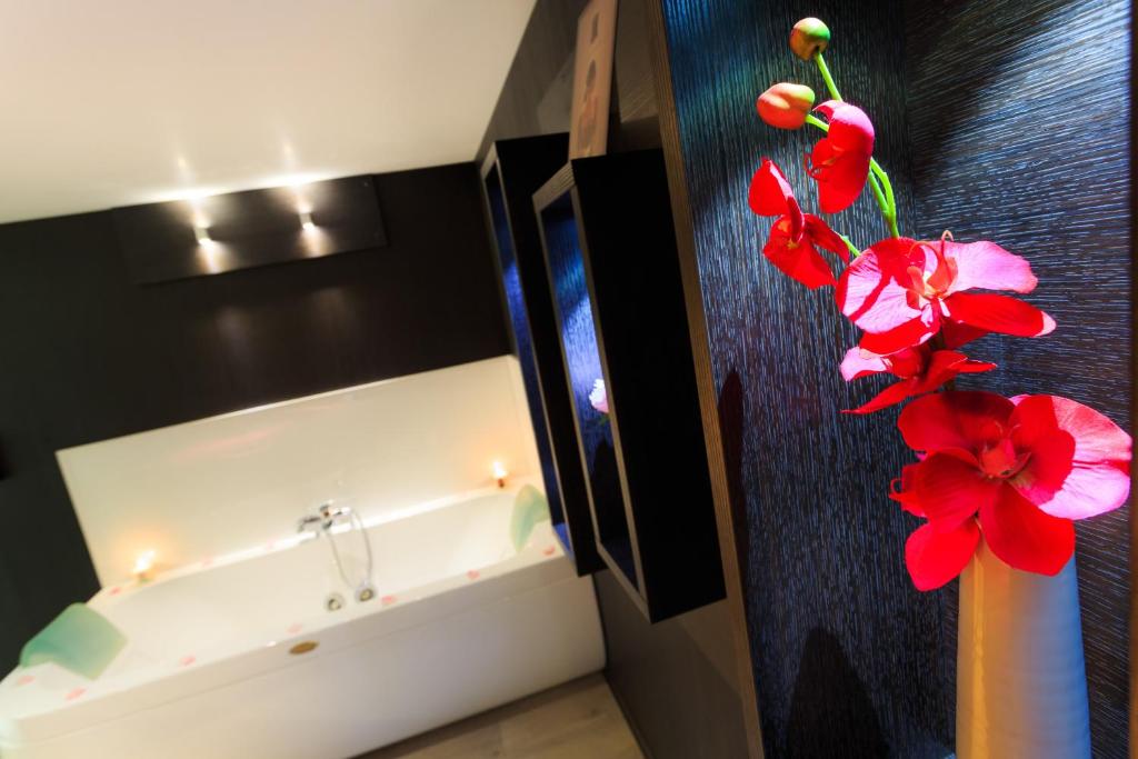 La salle de bains est pourvue d'un lavabo et d'un vase avec des fleurs rouges. dans l'établissement Frantheor Fréjus 5 étoiles, à Fréjus