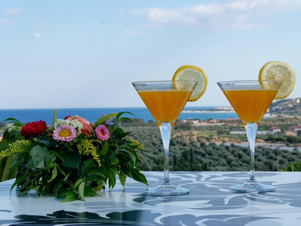 deux verres de jus d'orange sur une table avec des fleurs dans l'établissement Park Hotel Mirabeau, à Montepaone