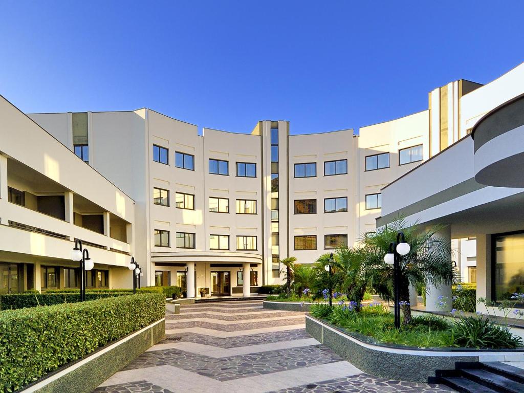 un grand bâtiment avec une allée devant dans l'établissement Park Hotel Mirabeau, à Montepaone