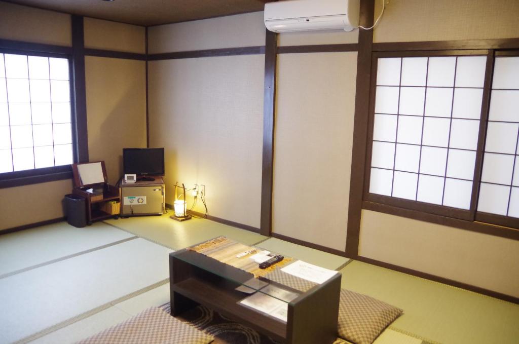 une pièce vide avec une table dans une pièce dotée de fenêtres dans l'établissement Ryoso Chatani, à Kyoto