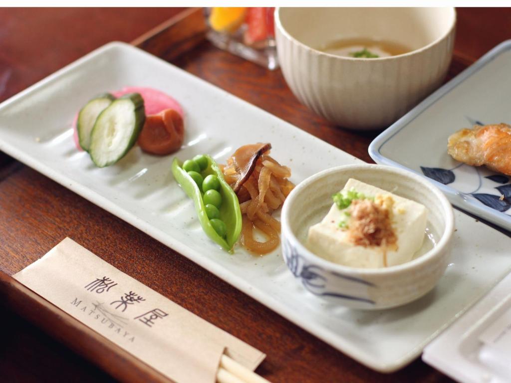 une assiette blanche avec un bol de nourriture sur une table dans l'établissement Oyado Matsubaya, à Minakami 98 autres photos
