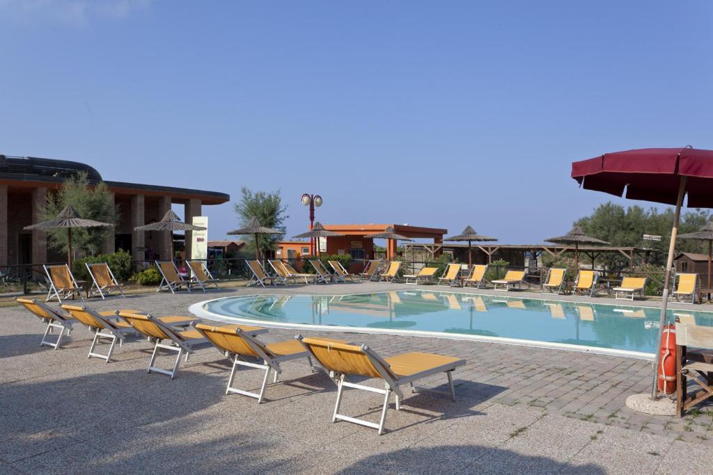 une grande piscine avec des chaises et un parasol dans l'établissement Toscana Sport Resort, à Tirrenia