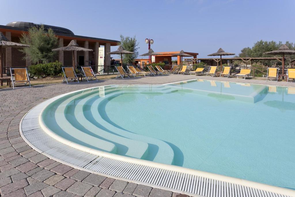 une grande piscine avec chaises et parasols dans l'établissement Toscana Sport Resort, à Tirrenia