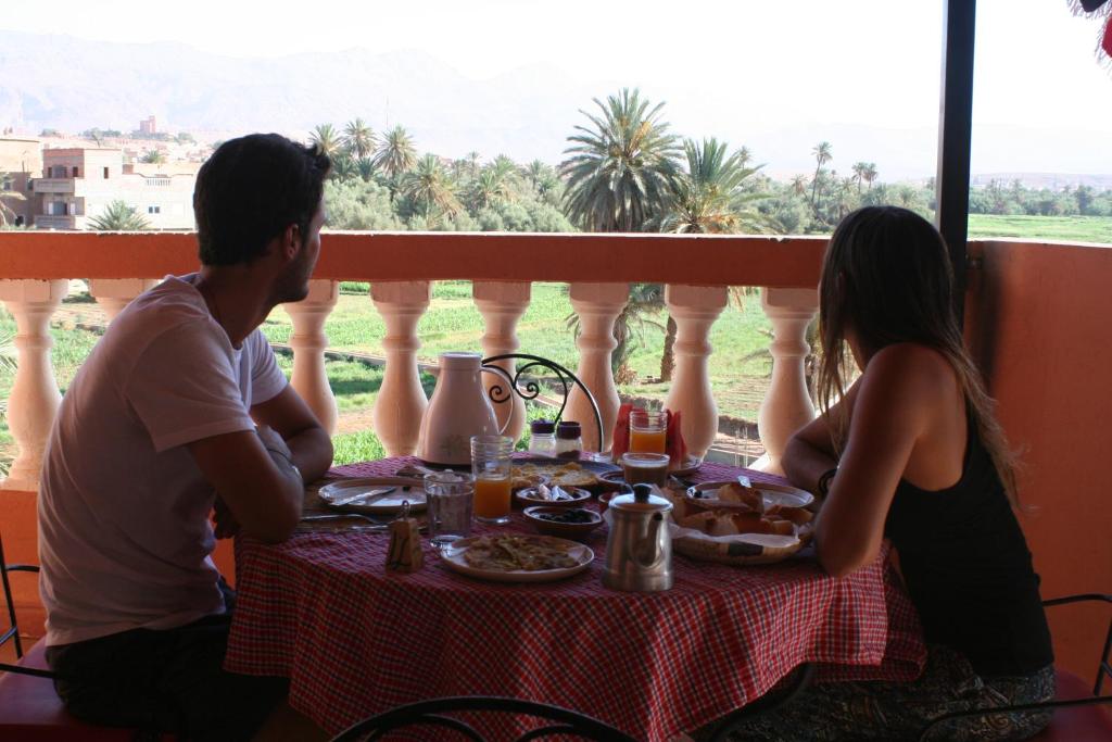 un homme et une femme assis à une table avec de la nourriture dans l'établissement Riad Al Anwar, à Tinghir