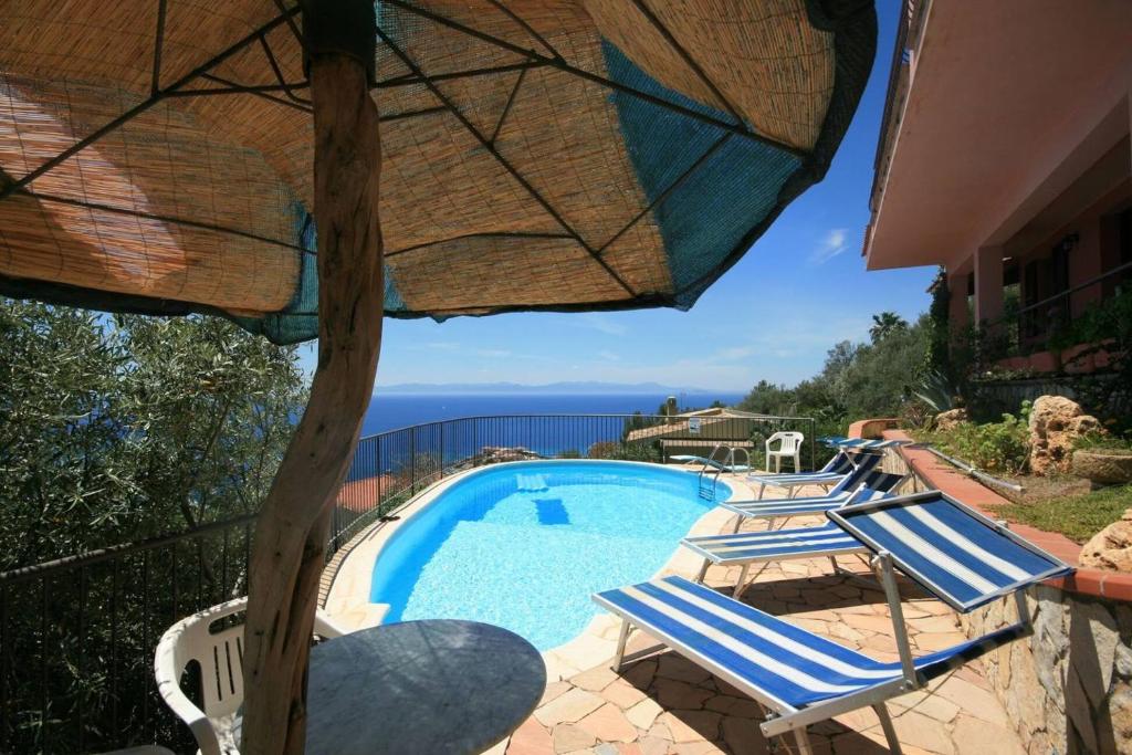 - une vue sur la piscine dotée de chaises et d'un parasol dans l'établissement Villa panoramica tra suggestive notti stellate., à Torre delle Stelle