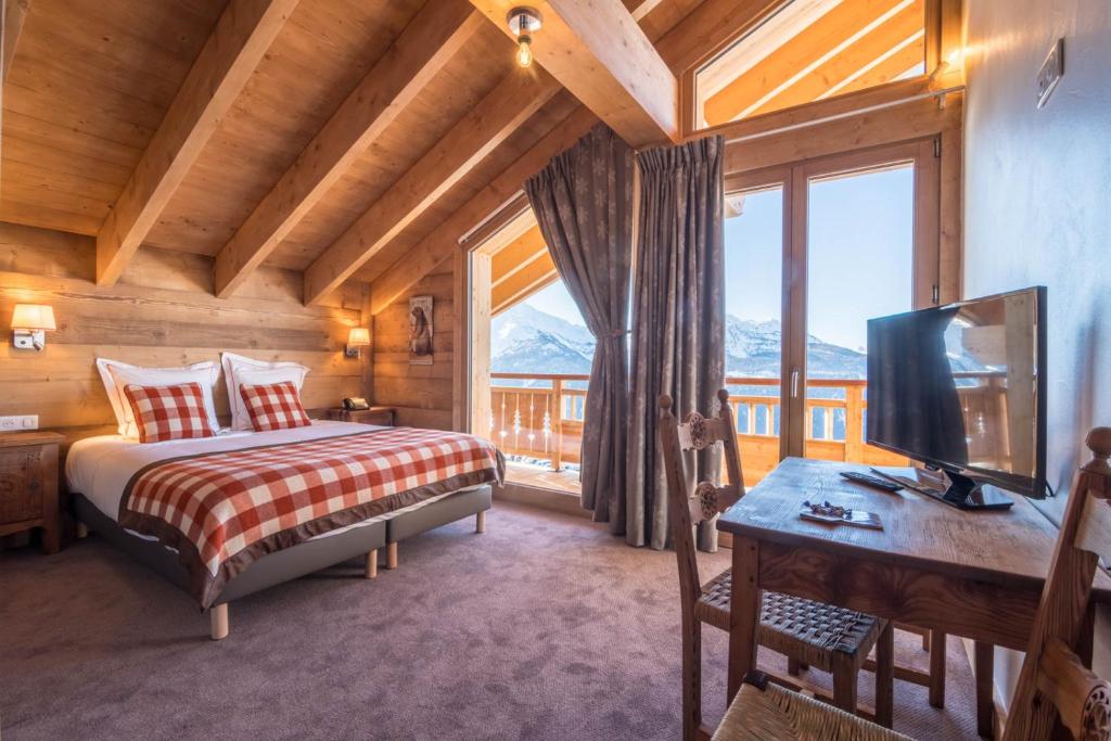 une chambre avec un lit et un bureau avec une télévision dans l'établissement Le Relais du Petit Saint Bernard, à La Rosière