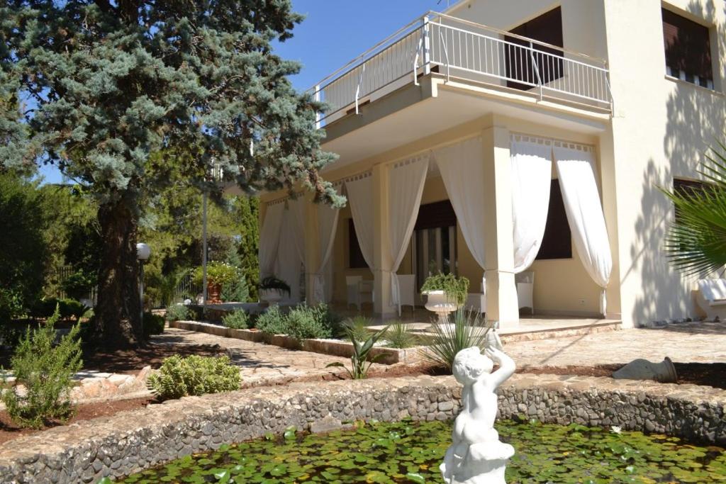 une statue dans un jardin en face d'un bâtiment dans l'établissement Villa panoramica con piscina, à Fasano