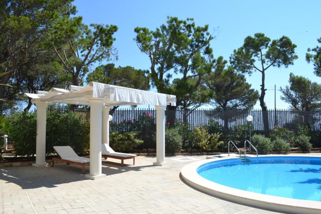 un gazebo et une piscine avec une table et une chaise dans l'établissement Villa panoramica con piscina, à Fasano