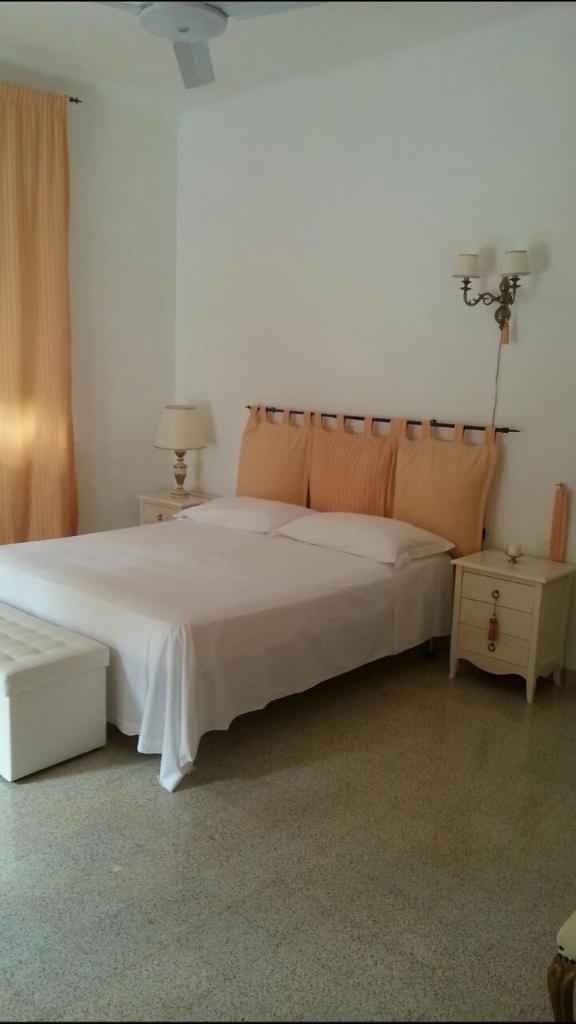 une chambre avec un grand lit blanc avec des oreillers orange dans l'établissement Villa panoramica con piscina, à Fasano