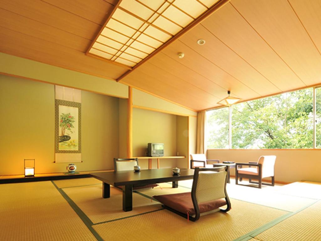 une pièce avec une table et des chaises et une grande fenêtre dans l'établissement Ginshotei Awashima, à Numata