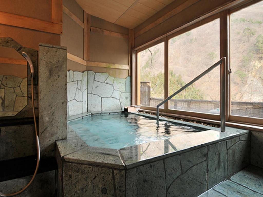 - un bain à remous dans une chambre avec fenêtre dans l'établissement Ginshotei Awashima, à Numata