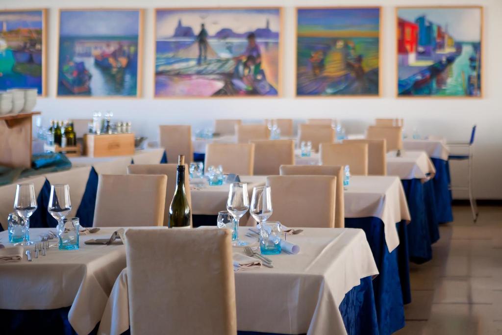 un restaurant avec des tables et des chaises blanches et des verres à vin dans l'établissement Hotel Garden Sea Wellness & Spa 4 stelle superior, à Caorle