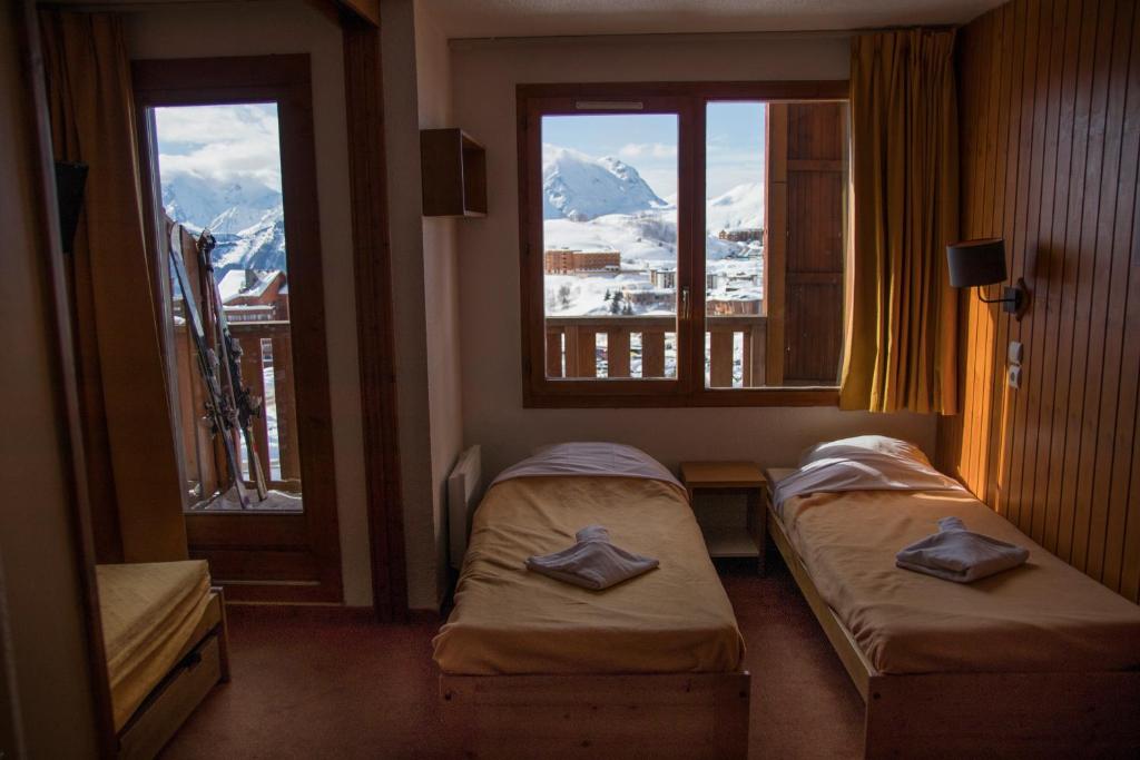 deux lits dans une chambre avec deux fenêtres dans l'établissement SUNWEB Résidence Les Bergers, à L'Alpe-d'Huez