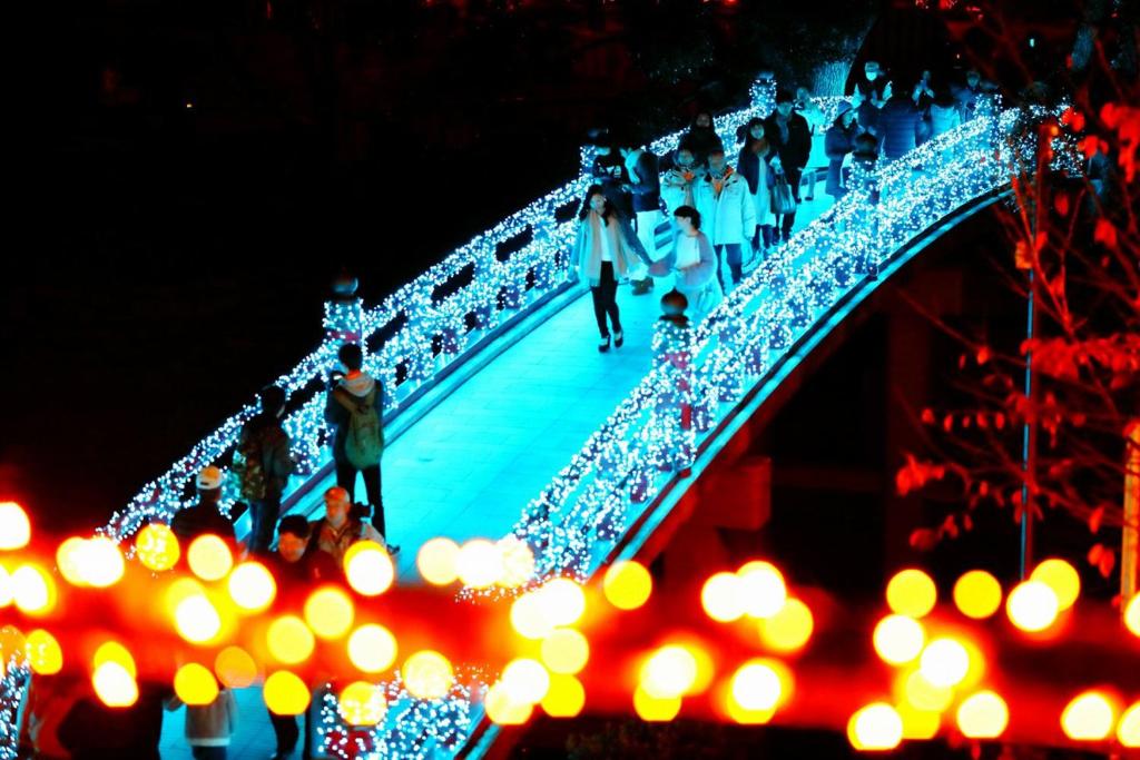 Un groupe de personnes marchant sur un pont aux lumières de Noël dans l'établissement Hotel Waltz Okazaki (Adult Only), à Okazaki