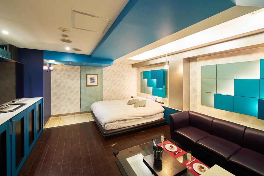 une chambre d'hôtel avec un lit et un canapé dans l'établissement Hotel AQUA Blue Yokosuka (Adult Only), à Yokosuka
