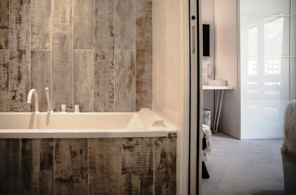 une salle de bain avec une baignoire blanche et une douche dans l'établissement Rock Noir & Spa, à La Salle Les Alpes