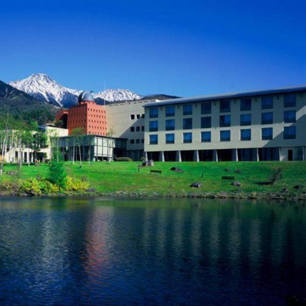 un grand bâtiment à côté d'un plan d'eau dans l'établissement Izumigo Kiyosato Kogen Hotel, à Hokuto