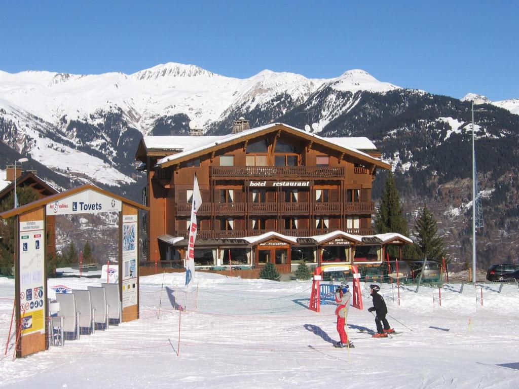 2 personnes à skis dans la neige devant un lodge de ski dans l'établissement Hotel les Flocons, à Courchevel